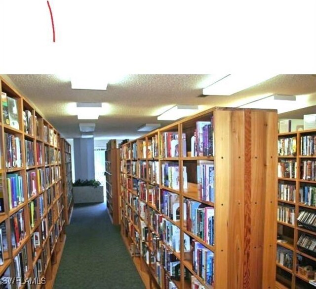 corridor with dark carpet and a textured ceiling