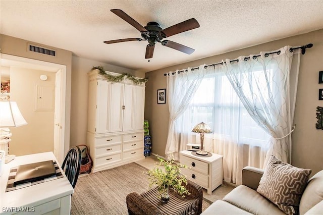 carpeted home office featuring ceiling fan and a textured ceiling