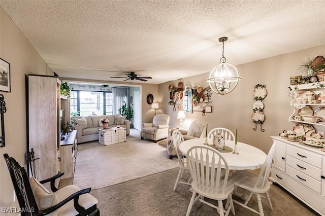 carpeted dining area with ceiling fan with notable chandelier and a textured ceiling