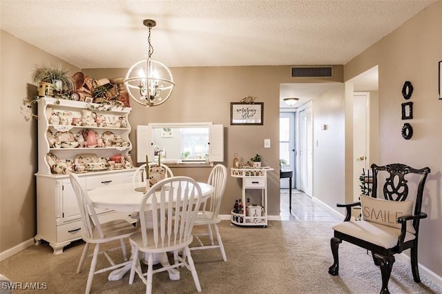 dining space with light colored carpet, a textured ceiling, and a chandelier