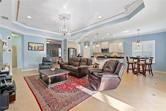 living area with ornamental molding, a tray ceiling, and an inviting chandelier