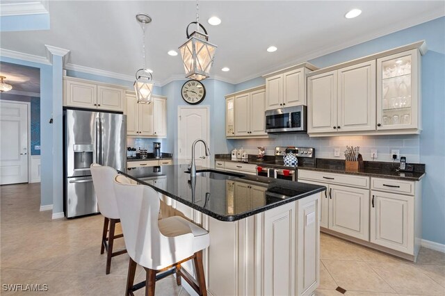 kitchen with sink, light tile patterned flooring, hanging light fixtures, a kitchen island with sink, and appliances with stainless steel finishes