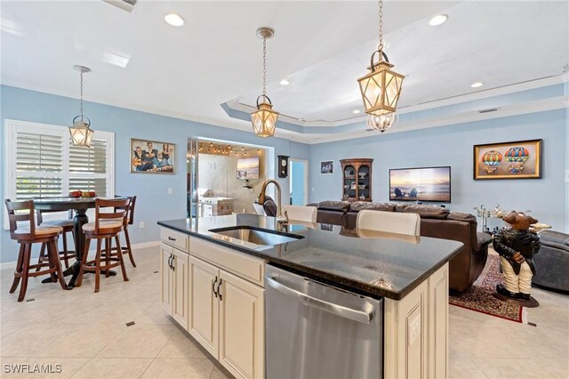 kitchen featuring a kitchen island with sink, a raised ceiling, hanging light fixtures, sink, and stainless steel dishwasher