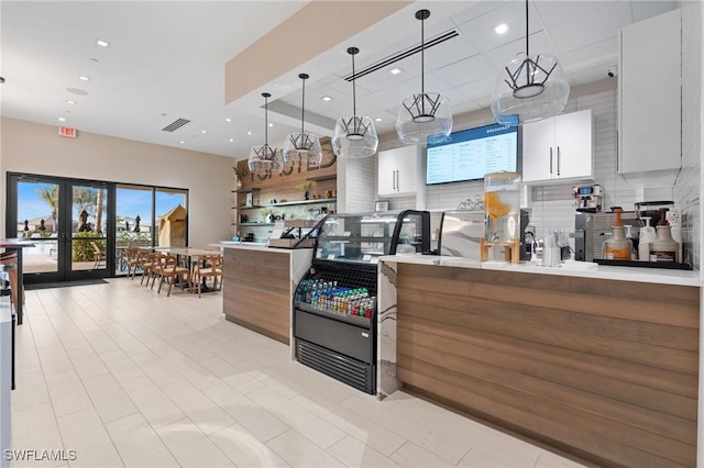 kitchen featuring white cabinets, pendant lighting, and a raised ceiling