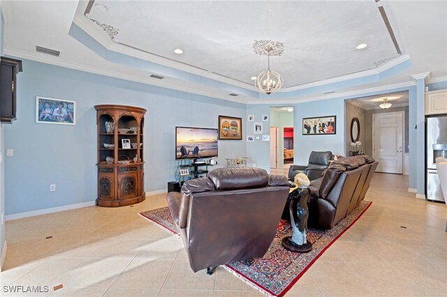 tiled living room featuring an inviting chandelier, ornamental molding, and a tray ceiling