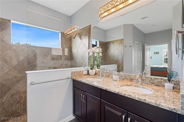 bathroom with a tile shower and vanity