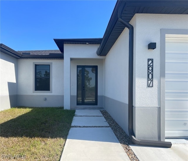 view of exterior entry with a garage and a yard