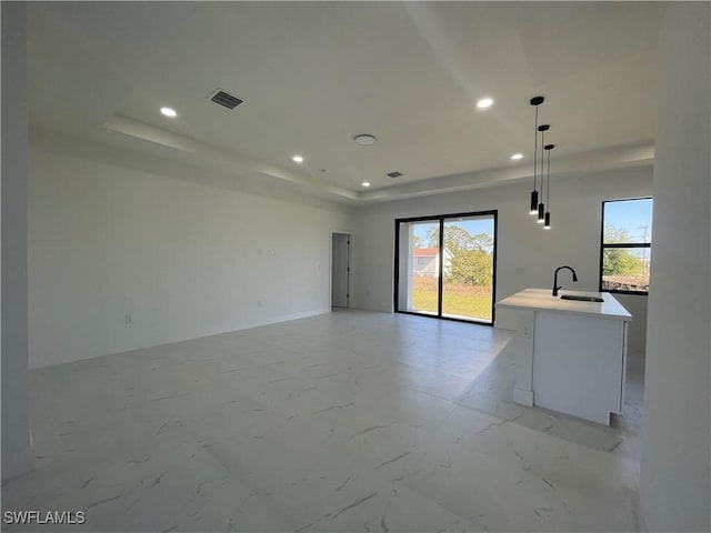 unfurnished living room featuring a tray ceiling and sink