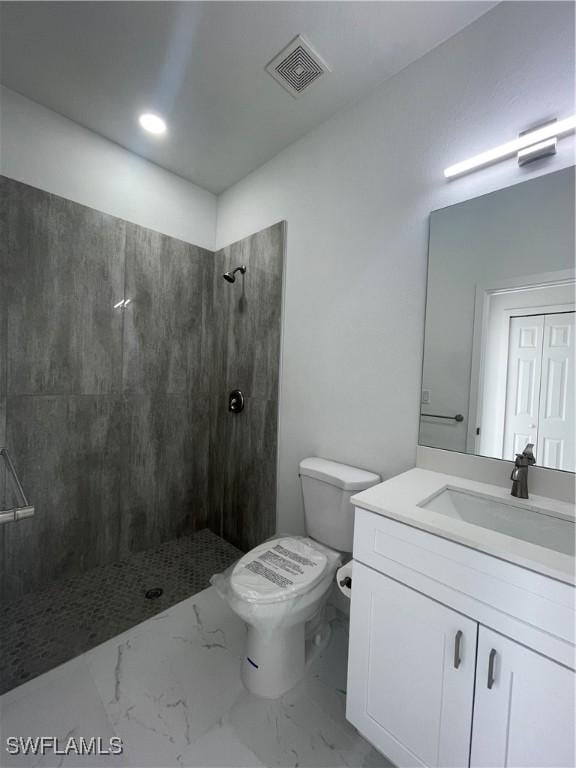 bathroom with toilet, vanity, and tiled shower