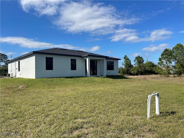 back of property featuring central air condition unit and a yard