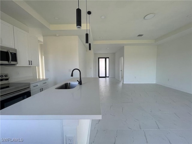 kitchen featuring sink, hanging light fixtures, electric range oven, a kitchen island with sink, and white cabinets