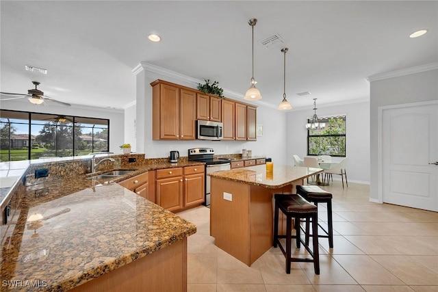 kitchen featuring sink, pendant lighting, stone countertops, ceiling fan with notable chandelier, and appliances with stainless steel finishes