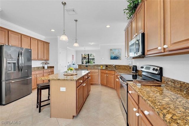 kitchen featuring a center island, a kitchen breakfast bar, crown molding, appliances with stainless steel finishes, and decorative light fixtures