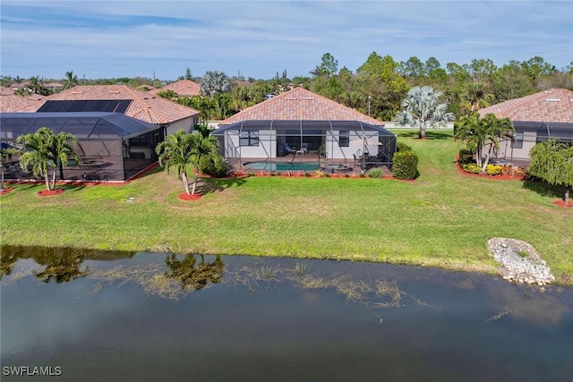 back of house featuring a yard, a water view, and a lanai