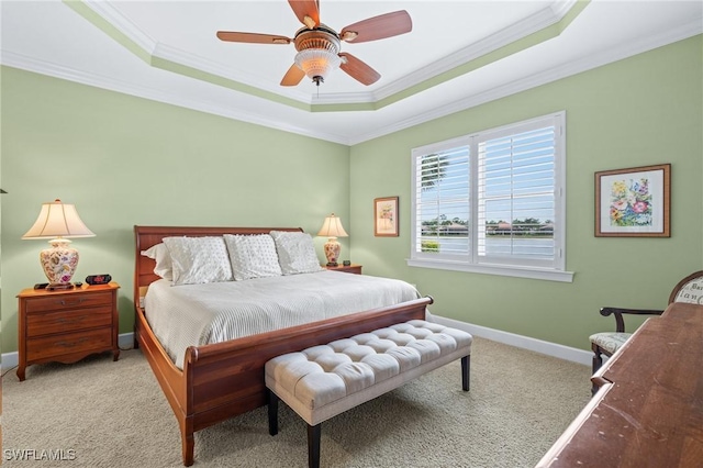 carpeted bedroom featuring ceiling fan, crown molding, and a tray ceiling