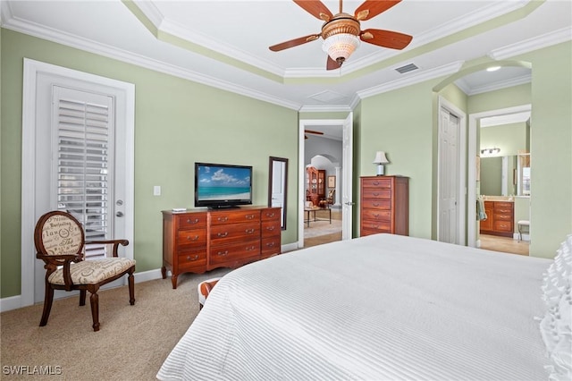 bedroom with ensuite bath, light carpet, ornamental molding, ceiling fan, and a tray ceiling