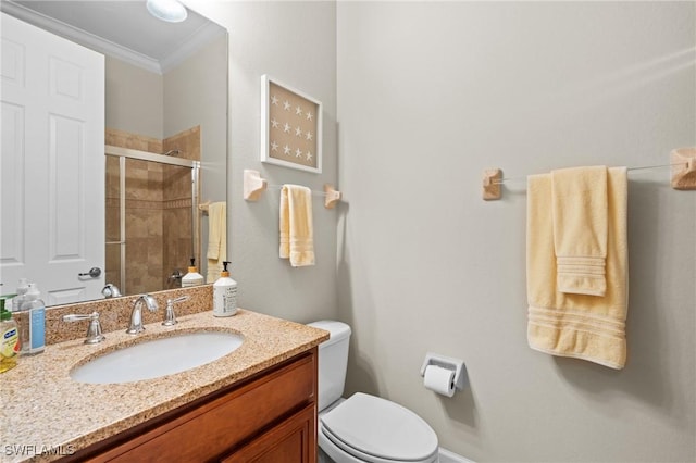 bathroom with toilet, a shower with door, ornamental molding, and vanity