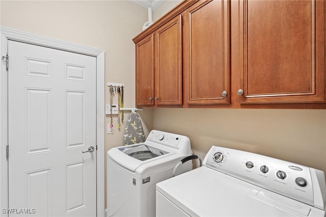 clothes washing area featuring cabinets, crown molding, and washing machine and clothes dryer