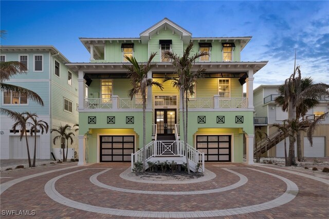 beach home with french doors, a balcony, a porch, and a garage