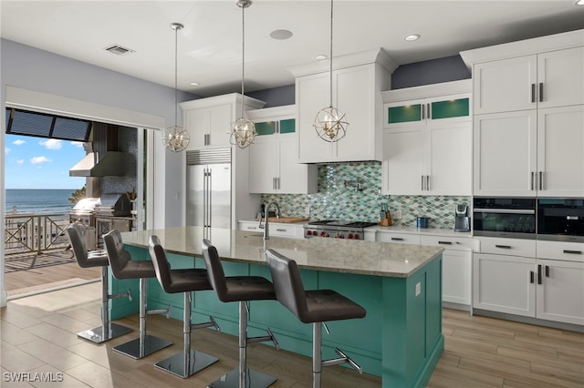 kitchen featuring a water view, appliances with stainless steel finishes, a kitchen bar, and a center island with sink