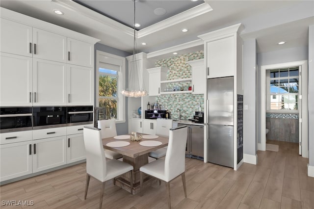 kitchen featuring appliances with stainless steel finishes, decorative light fixtures, a raised ceiling, and white cabinets