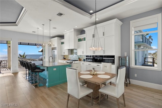 kitchen featuring white cabinetry, an island with sink, a breakfast bar, and decorative light fixtures