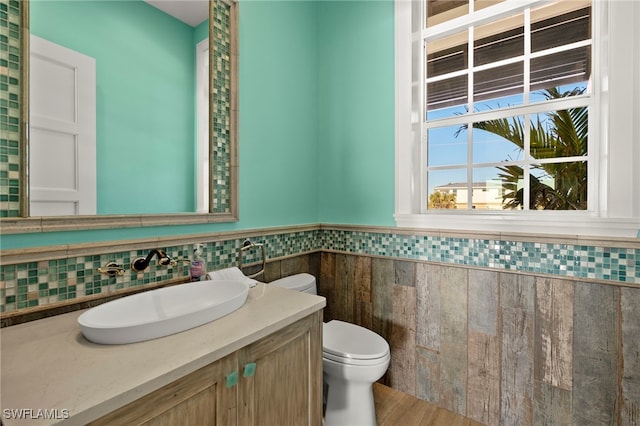 bathroom with vanity, tile walls, and toilet