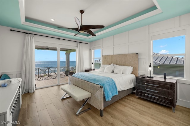 bedroom with a water view, a raised ceiling, and access to outside