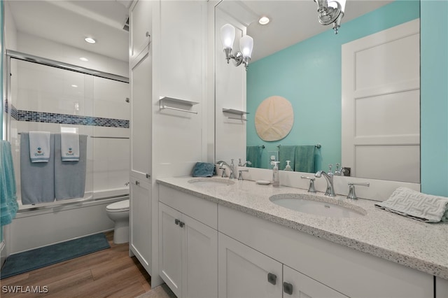 full bathroom with vanity, wood-type flooring, shower / bath combination with glass door, and toilet