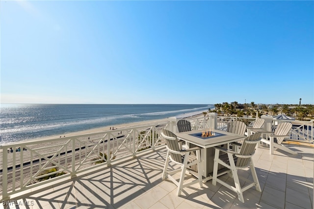 balcony featuring a water view, a beach view, a patio, and an outdoor fire pit