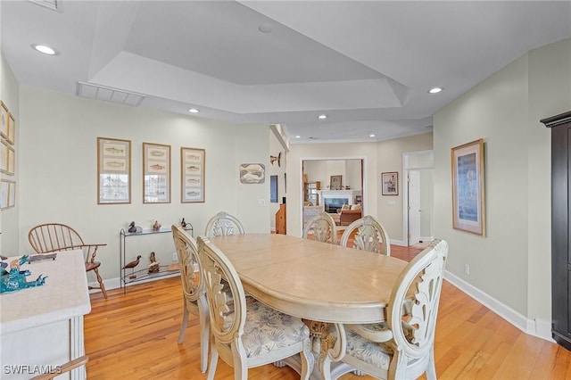 dining area with a tray ceiling and light wood-type flooring