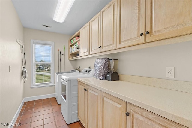 laundry room featuring washer and clothes dryer, light tile patterned floors, and cabinets