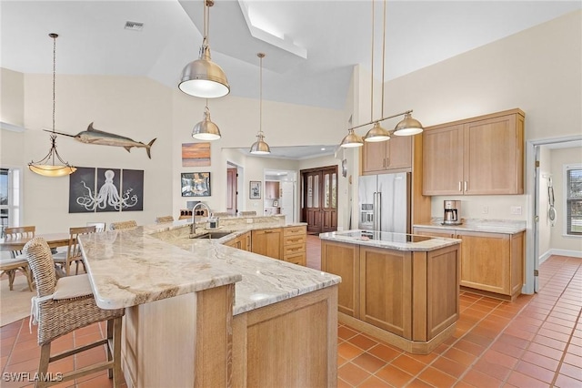 kitchen featuring high end fridge, a spacious island, sink, light tile patterned floors, and hanging light fixtures