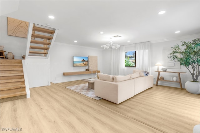 living room featuring a notable chandelier, light wood-type flooring, and crown molding