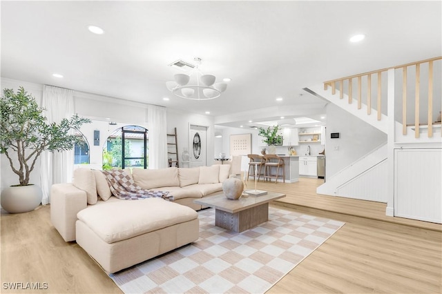 living room with light wood-type flooring, a chandelier, and sink