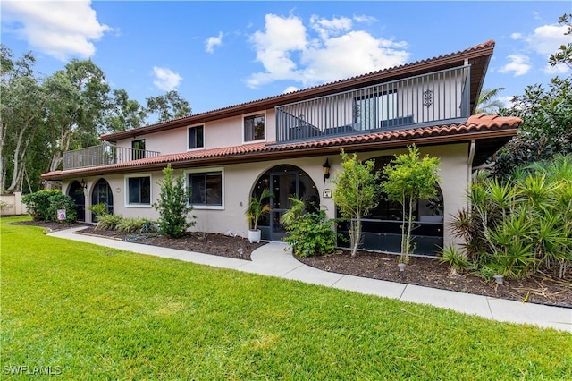 view of front of property featuring a balcony and a front lawn