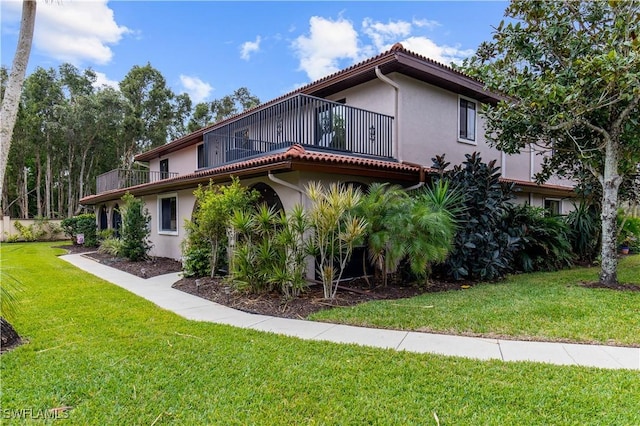 exterior space featuring a balcony and a front yard