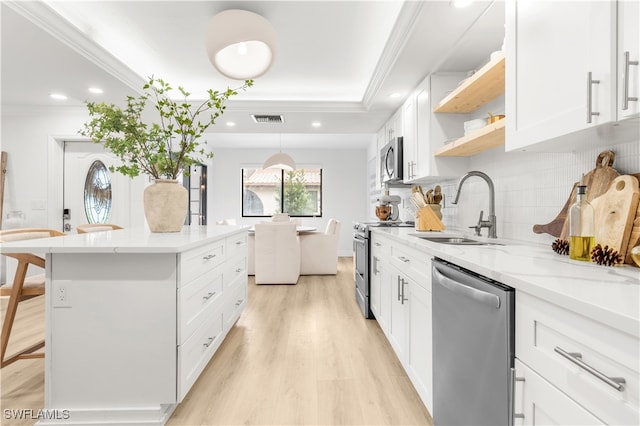 kitchen with backsplash, white cabinets, appliances with stainless steel finishes, a kitchen breakfast bar, and sink