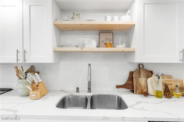 kitchen featuring sink, white cabinetry, tasteful backsplash, and light stone countertops