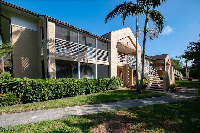 view of front facade with stairs, a front lawn, and stucco siding