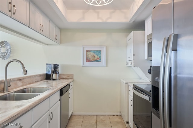 kitchen with sink, white cabinetry, stainless steel appliances, and a tray ceiling