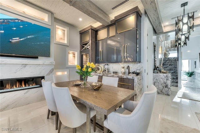 tiled dining room with beam ceiling and a fireplace