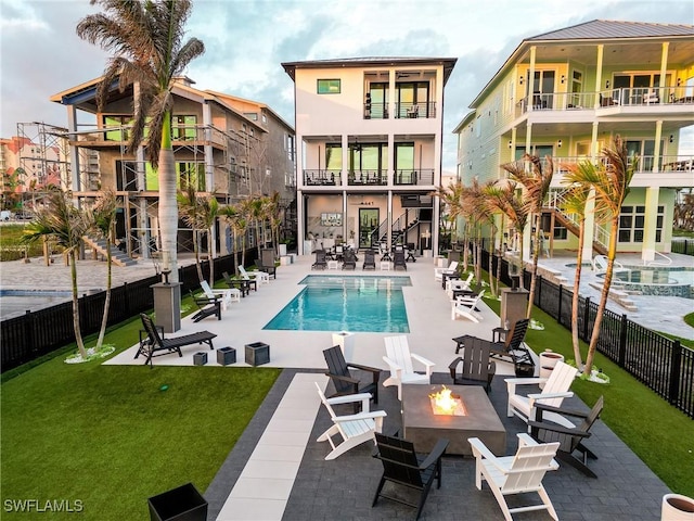 back of house featuring a community pool, a fire pit, a lawn, and a patio