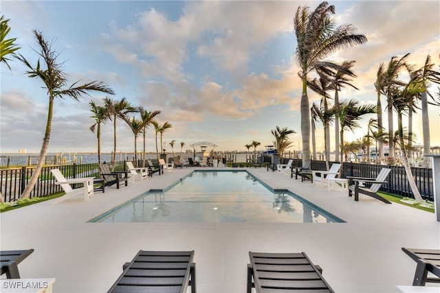 pool at dusk with a patio area