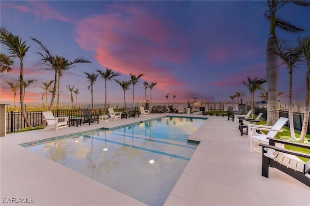 pool at dusk featuring a patio area