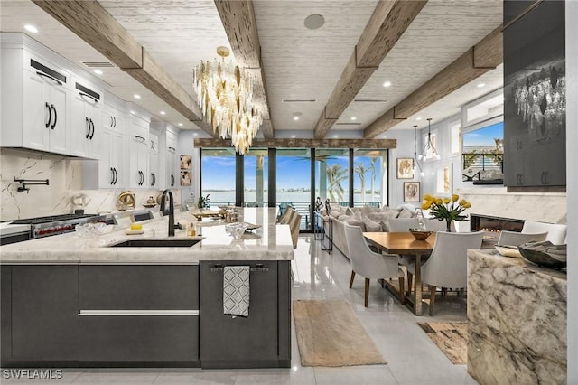kitchen with beamed ceiling, white cabinets, light stone counters, a sink, and decorative backsplash