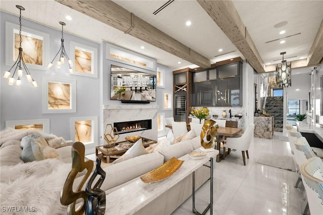 living area featuring beam ceiling, recessed lighting, a notable chandelier, and a high end fireplace