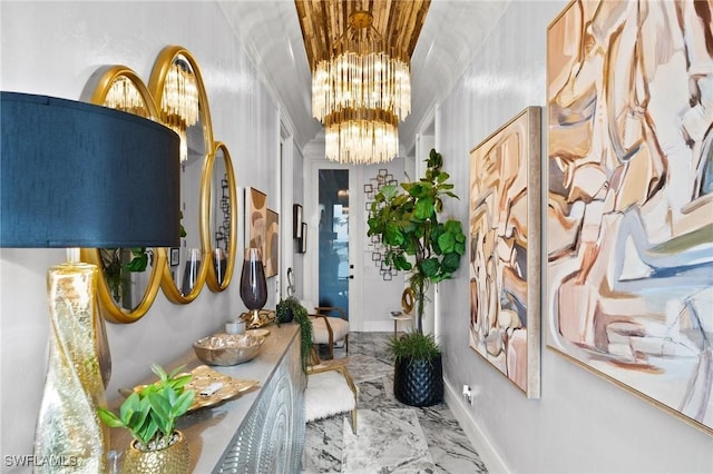 hallway with baseboards, marble finish floor, and a notable chandelier