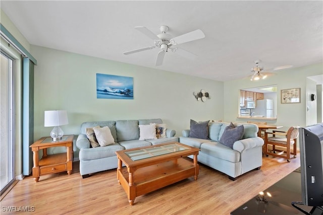 living room featuring ceiling fan, a wealth of natural light, and light hardwood / wood-style flooring