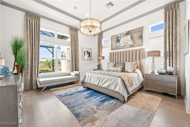 bedroom with hardwood / wood-style flooring and an inviting chandelier